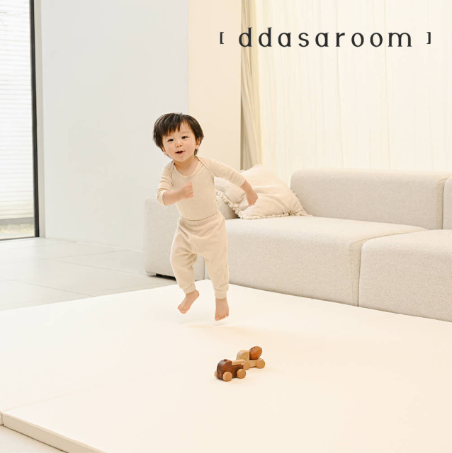 밝은 거실에서 따사룸 매트 위를 뛰노는 아이